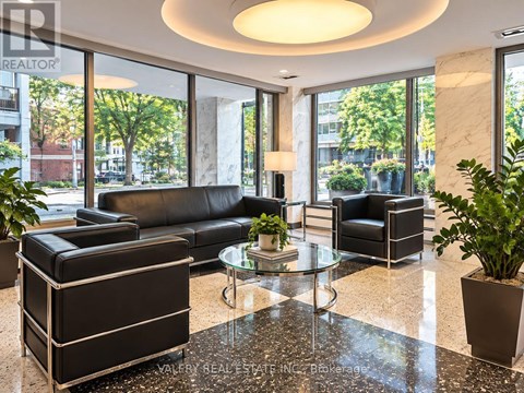 A living room with a black couch and a glass table.