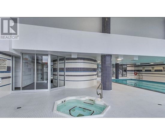 A swimming pool in a room with a glass door.