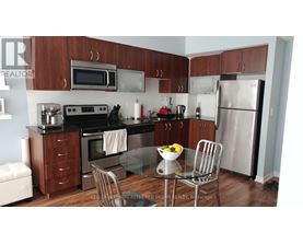 A kitchen with a refrigerator, oven, and microwave.
