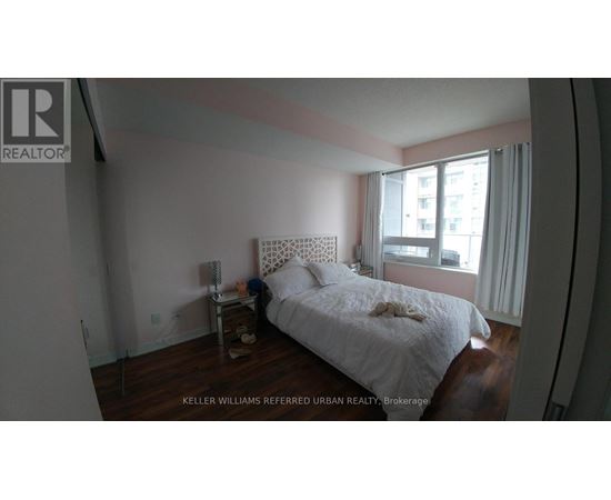 A bedroom with a white bed and a window with white curtains.