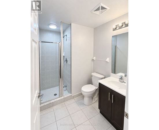 A white bathroom with a toilet, sink, and shower.