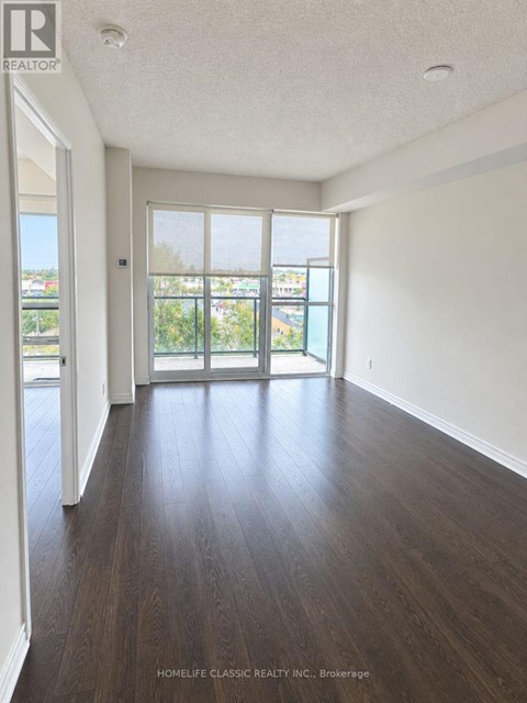A room with wooden floors and a sliding glass door leading to a balcony.
