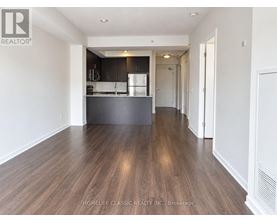 A spacious kitchen with dark wood floors and white walls.
