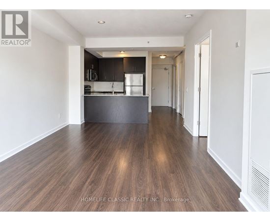 A spacious kitchen with dark wood floors and white walls.
