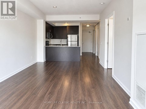 A spacious kitchen with dark wood floors and white walls.