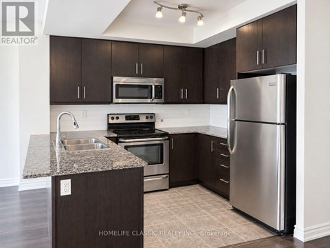 A kitchen with dark brown cabinets and stainless steel appliances.