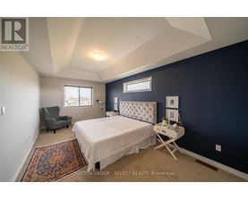 A bedroom with a bed, chair, and window.