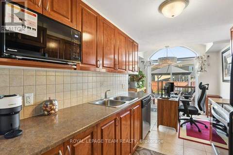 A kitchen with wooden cabinets and a black microwave.