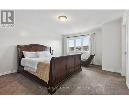 A bedroom with a large bed and a window overlooking a residential area.