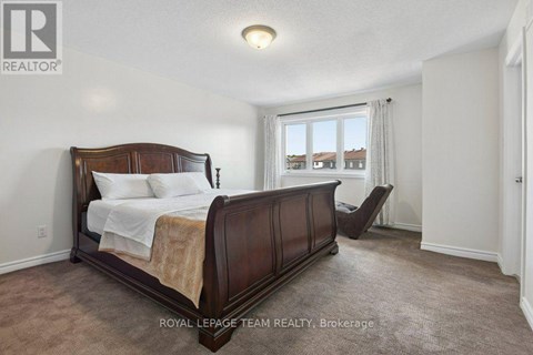 A bedroom with a large bed and a window overlooking a residential area.