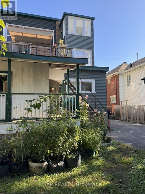 A house with a balcony and potted plants in front.