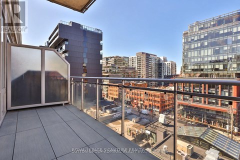 A balcony with a glass railing overlooks a cityscape.