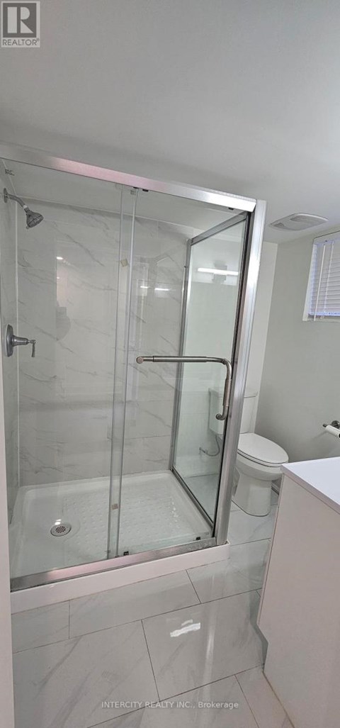 A bathroom with a glass shower door and a white toilet.