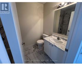 A bathroom with a toilet, sink, and mirror.