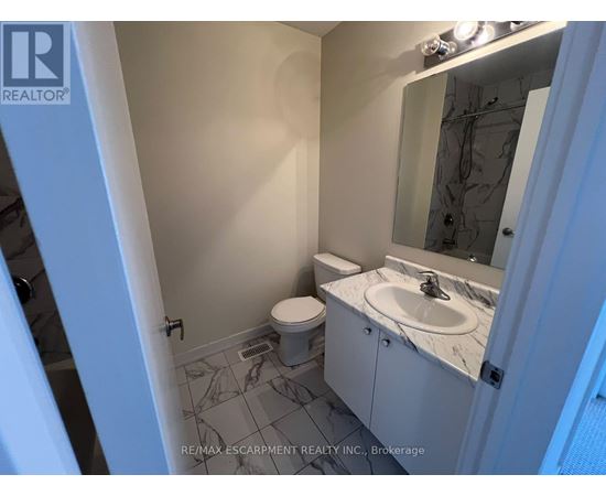 A bathroom with a toilet, sink, and mirror.
