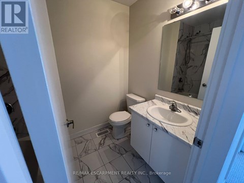 A bathroom with a toilet, sink, and mirror.