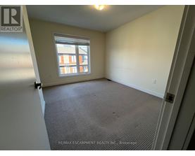 A room with a window and a carpeted floor.