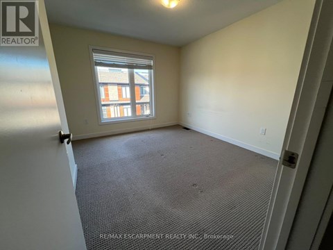 A room with a window and a carpeted floor.