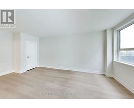 A room with a white door and a window with a view of the street.