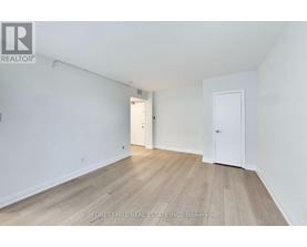 A white room with wood flooring and two doors.