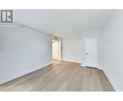 A white room with wood flooring and two doors.