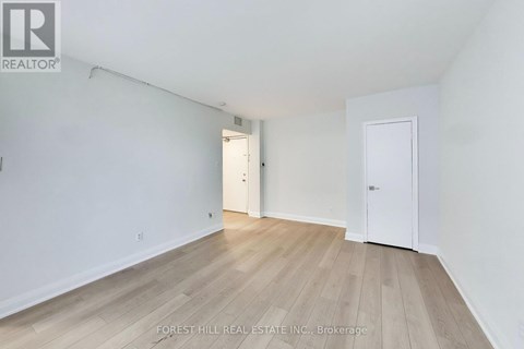 A white room with wood flooring and two doors.