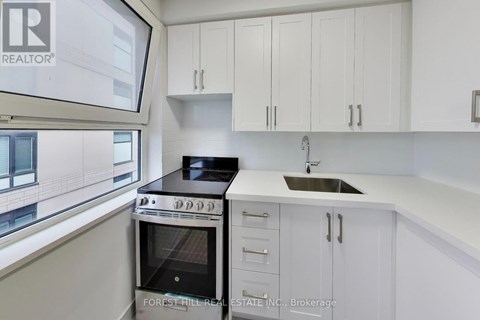A modern kitchen with white cabinets and a stove top oven.