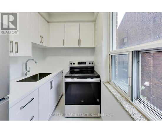 A kitchen with white cabinets and a black stove top oven.