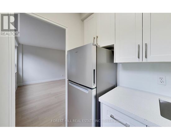 A kitchen with a refrigerator and a stove top oven.