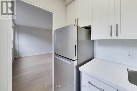 A kitchen with a refrigerator and a stove top oven.