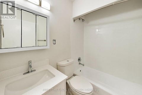 A white bathroom with a sink, toilet and bathtub.