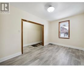 A room with a doorway leading to another room and a window with a view of a building outside.