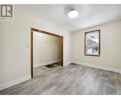 A room with a doorway leading to another room and a window with a view of a building outside.