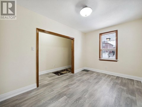 A room with a doorway leading to another room and a window with a view of a building outside.