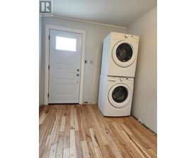 A white door and a washing machine in a room with wooden flooring.
