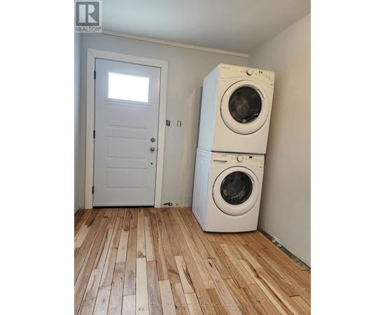 A white door and a washing machine in a room with wooden flooring.