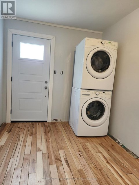 A white door and a washing machine in a room with wooden flooring.