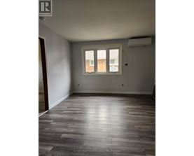 A room with a window and wooden flooring.