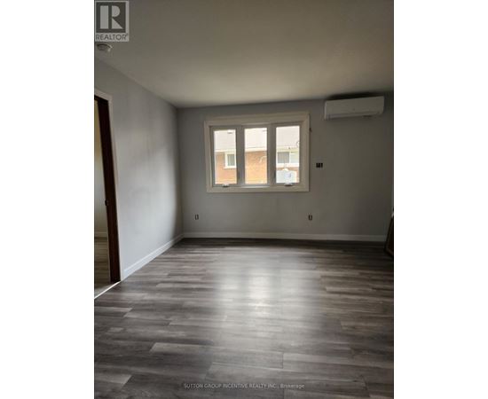 A room with a window and wooden flooring.