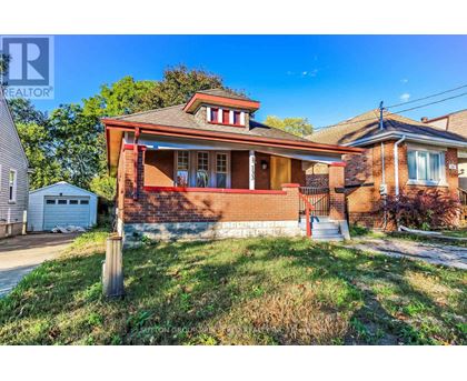 A house with a red brick exterior and a white garage door is for sale.