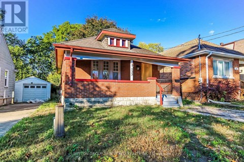 A house with a red brick exterior and a white garage door is for sale.