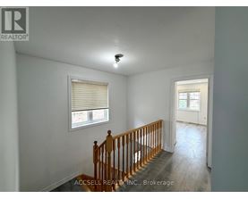 A room with a wooden staircase and a window with blinds.