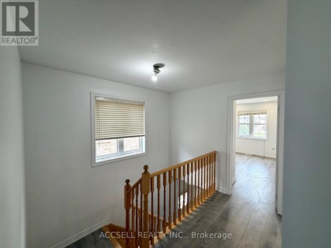 A room with a wooden staircase and a window with blinds.