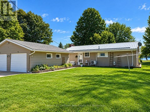 A house with a garage and a covered patio is surrounded by a green lawn.