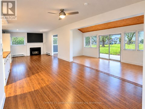 A spacious room with wooden floors and a fireplace.