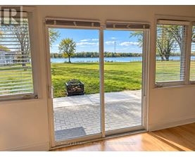 A patio door with a view of a grassy area and a lake.