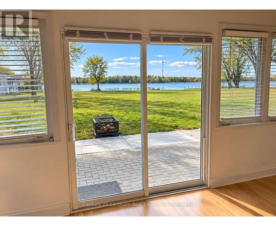 A patio door with a view of a grassy area and a lake.