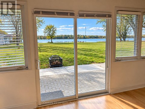 A patio door with a view of a grassy area and a lake.