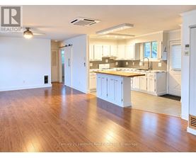 A spacious kitchen with white cabinets and a wooden floor.