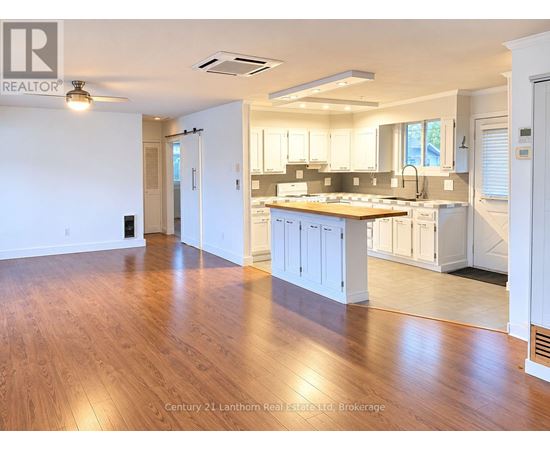 A spacious kitchen with white cabinets and a wooden floor.